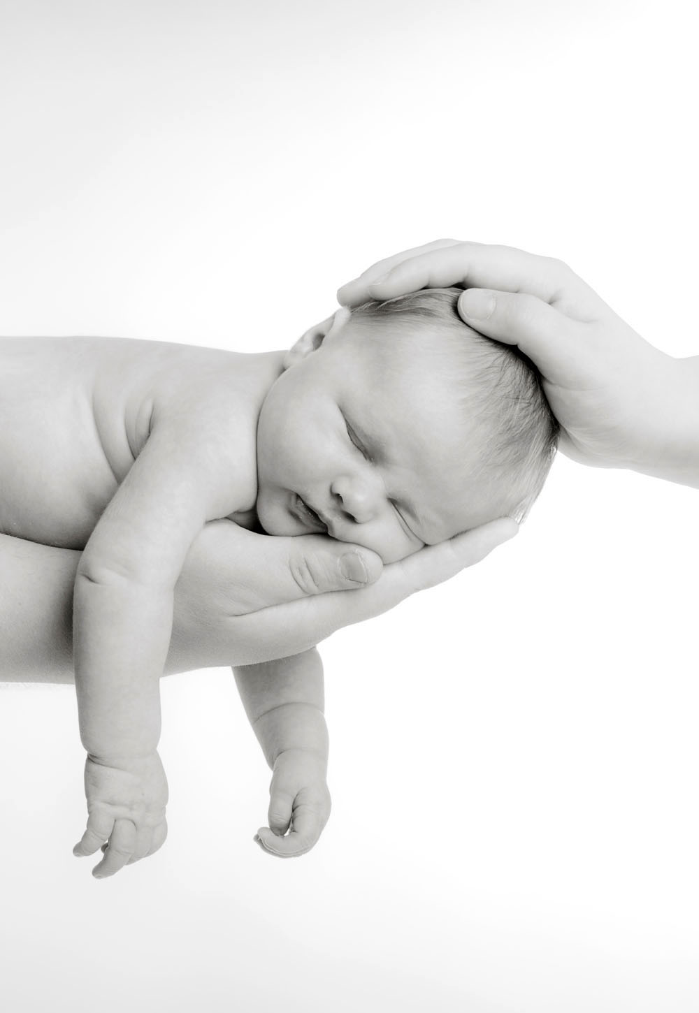 Neugeborenenfoto auf dem Arm des Vaters. Baby schläft und Mutter hat ihre Hand auf dem Kopf des Neugeborenen. Fotografiert in unserem Fotostudio in Weinheim